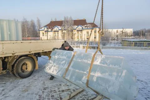 Slinger in a blue jacket unloading ice blocks 스톡 사진
