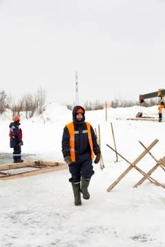Slinger in an orange helmet walks down the assembly site 스톡 사진