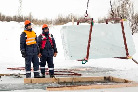 Slingers control the rise of ice blocks. Fotos Stock