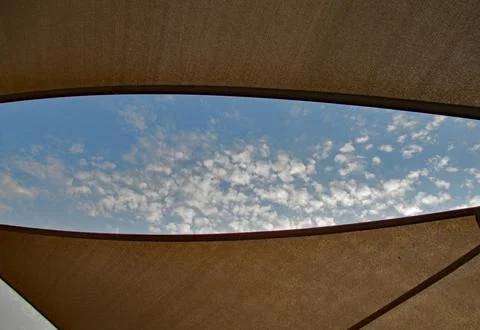 A slit between two sails shows light clouds in a blue sky 스톡 사진