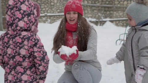 Slo-mo authentic cute happy young woman mom in red hat with children take snow Video stock 153822436