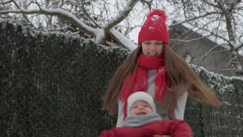 Slo-mo authentic cute young woman mom in red hat holding spinning little happy Stock Footage 152856724