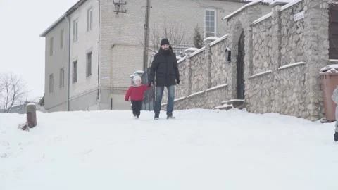 Slo-mo authentic happy young man dad in black with baby son run down on snowy Stock Footage 152999352