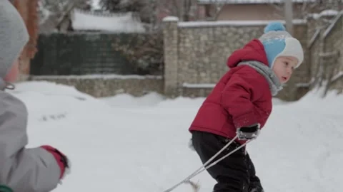 Slo-mo authentic little boy 2-3 years old pulls sled with kids by the rope Stock Footage 152897919