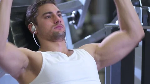 Slo-Mo of handsome young man on shoulder press machine Stock Footage 85316656