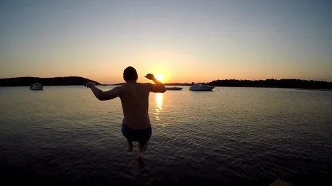 SLO MO Jumping from a pier into the water at sunset Stock Footage 92416632