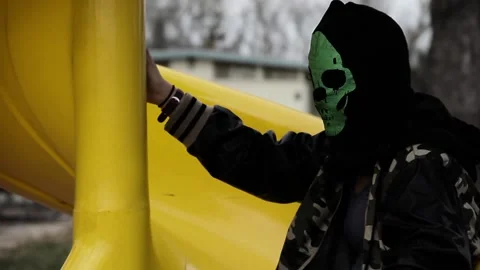 Slo-mo shot of kid in creepy mask going down slide Stock Footage 155489645
