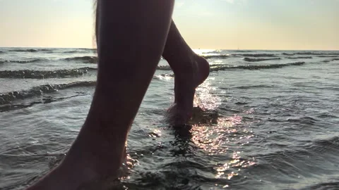 SLO MO TS Man walking barefoot on the sandy beach at sunset Stock Footage 234720074