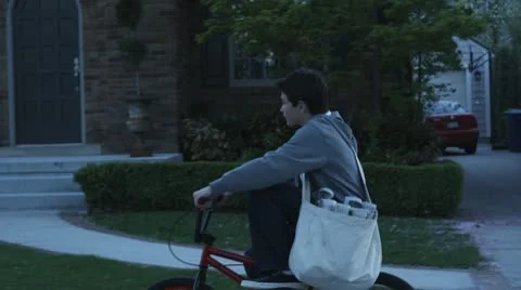 SLO MO, TS, MS, paperboy riding his bike past houses Stock Footage 10703273
