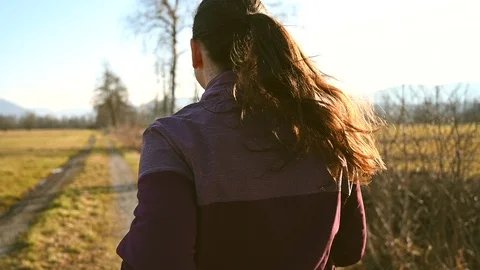 SLO MO TS: Right behind shot of a woman with a long pony tail running across the Stock Footage 125254183