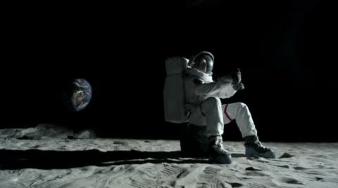 SLO MO, WS, PAN astronaut sitting on a rock on the moon lighting a sparkler Stock Footage 10700538