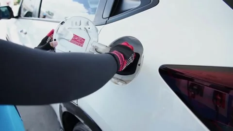 SLO MO Young uses her smartphone while she re-filling fuel in her car Offroad Stock Footage 336569816