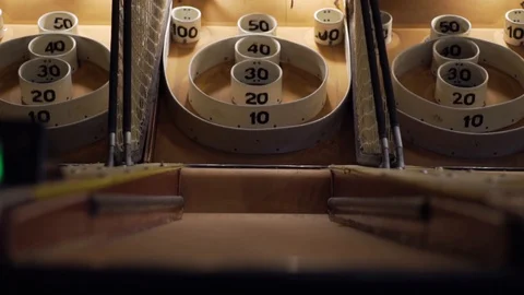 Slo-motion low angle shot of a skee-ball rolling down the ramp into the baskets. Stock Footage 93239426