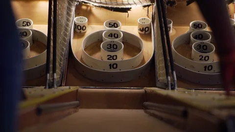 Slo-motion low angle shot of a girl reaching and grabbing a skee-ball and then Stock Footage 93239443