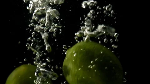 Slo-motion whole lemon and lime falling on water Stock Footage 80428393
