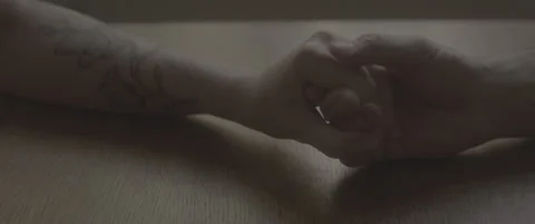 SLog shot of two hands gently holding each other on a wooden table Stock Footage 302344196