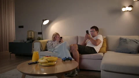 Slomo: Competitive Couple Playing Mobile Games On Their Smartphones At Home Stock Footage 135735518