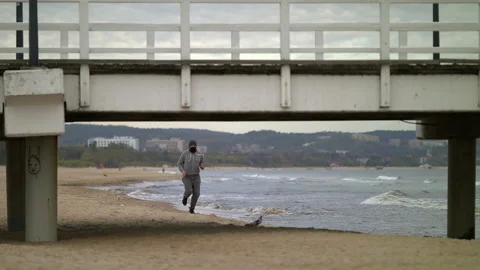 SloMo: Man with Beard in Protective Face Mask Running by the Beach at Dusk - Stock-Footage 130732246