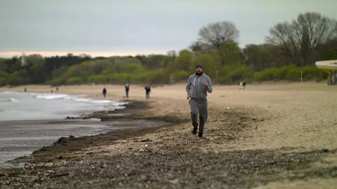 SloMo: Man with Beard Running by the Beach at Dusk - Wide Shot Stock Footage 130728113