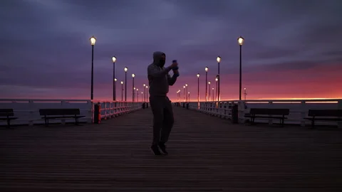 SloMo: Man In Tracksuit Training with Weights on a Seaside Pier at Dusk - Wide Stock Footage 130730018