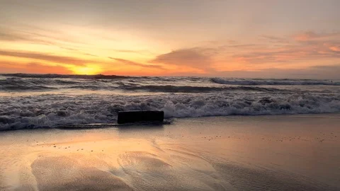 Slomo of powerful waves splashing on tree trunk in the beach during sunset Stock Footage 125842697