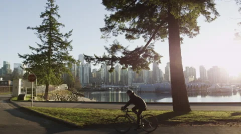 Slomo - Vancouver Skyline Sunset Park Cyclist - 01 Stock Footage