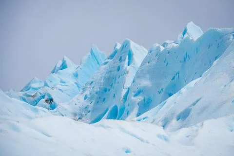 Slopes of the blue glacier against the sky. Shevelev. Stock Photos