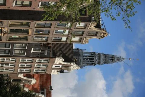 Sloping facade of a brick house. In the background the tower of Foto stock