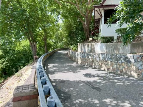 Sloping path alongside Thai architectural building hidden under the canopy Stock Photos