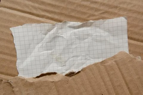 Sloppily torn rectangular-shaped graph paper on a cardboard texture Stock Photos