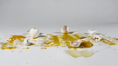 Sloppy broken eggs and egg shells on white seamless background Stock Footage 304233033