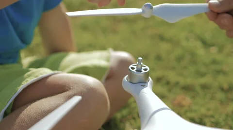 Сlose up: father with adorable son assembling modern drone on the green lawn. Stock-Footage 61449468