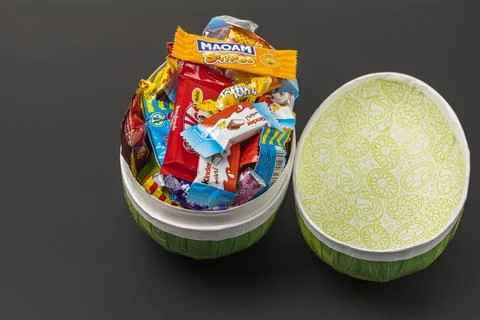 Сlose up view of an open Easter egg with sweets isolation on black background. Stock Photos
