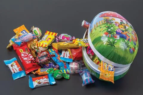 Сlose up view of an open Easter egg with sweets isolation on black background. Stock Photos