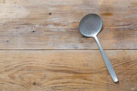 Slotted spoon on rustic wood background in bird's eye view Stock Photos