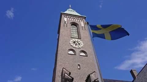 Slow 120fps Low-Angle Shot of Swedish Flag Waving on Church Tower Vídeo Stock 309454384