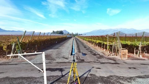 Slow advancing shot past a GNSS surveying tripod along a rural farm road Stock Footage 340396821