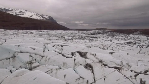 Slow aerial backwards moving shot flying low over glacier in Iceland. cloudy day Video stock 89227714