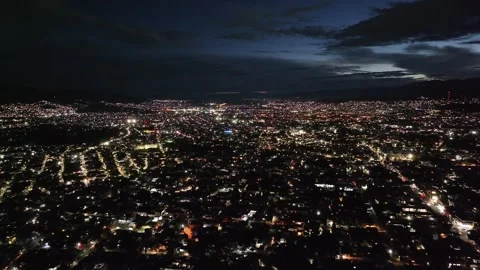 Slow aerial flight over Oaxaca City at dusk with city lights Видео 260421247