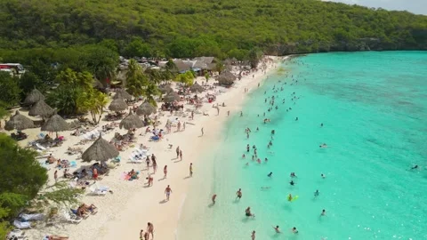 Slow Aerial Flyover Above Crowded Playa Cas Abao Beach with Palapas and Stock Footage 337754889