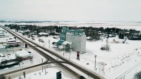 Slow aerial orbiting view of vintage grain elevator amid snowy farmland Stock Footage 296626423
