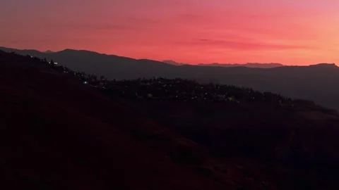 A slow aerial pan left capturing a vivid pink sunset sky, with tiny twinkles of 스톡 동영상 300301740
