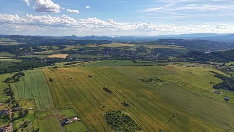 Slow aerial sweep over patchwork countryside with farmland valley, scattered Stock Footage 342358573