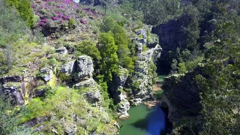 Slow and smooth aerial, while follwing a river through a rocky canyon Stock Footage