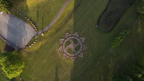 Slow Ascending Drone Shot of Stone Sun Symbol on Grass Stock Footage 313623602
