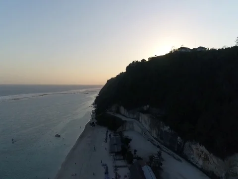 Slow ascent over beach, cliffs, and ocean toward sunset in Bali, Indonesia. Stock Footage 80177231