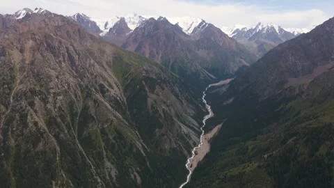 Slow ascent from a river gorge to snow-capped peaks Video stock 248474687