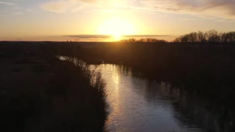 Slow Backward Drone Flight Over Wide River with Golden Reflections at Sunset Stock Footage 325330905
