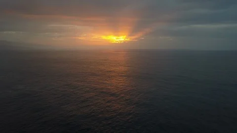 Slow backward flight above ocean waves towards beautiful colourful sunset Stock Footage 114895969
