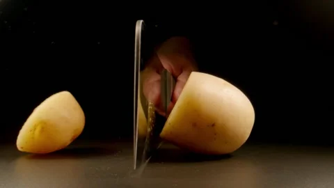 SLOW: Big knife cuts a row potato on a black background Stock Footage 201855777